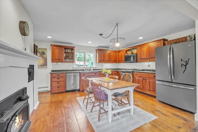 kitchen featuring a breakfast bar, stainless steel appliances, a baseboard radiator, and light hardwood / wood-style floors