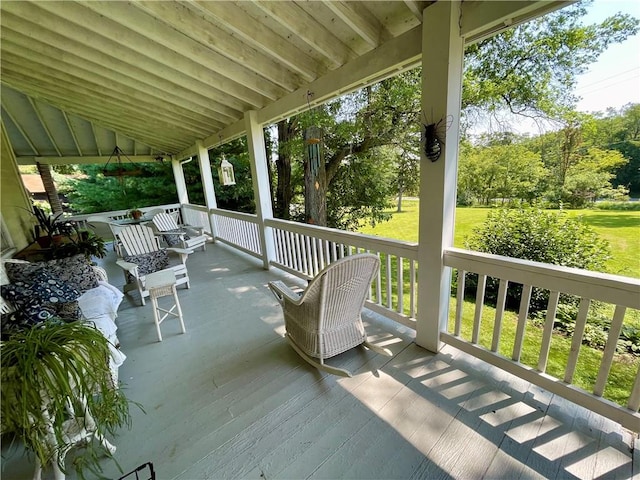 wooden deck with covered porch and a lawn