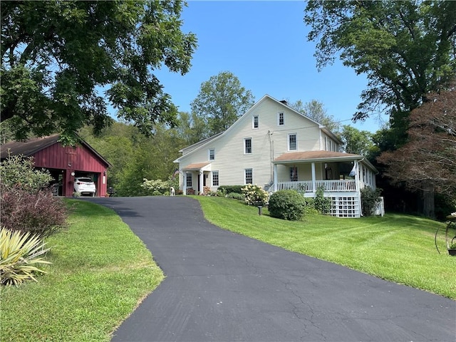 view of home's exterior with covered porch, a garage, an outdoor structure, and a yard