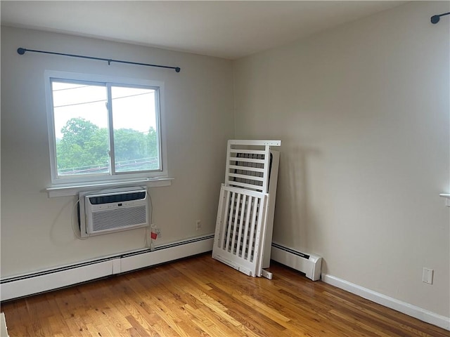 empty room with light wood-type flooring, a wall unit AC, and a baseboard heating unit