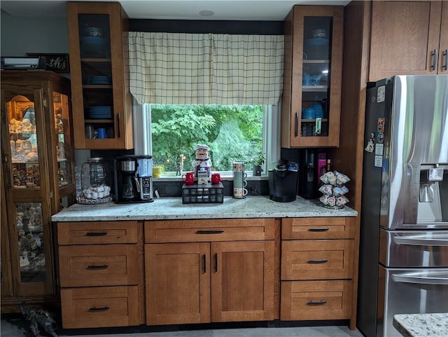 kitchen featuring light stone counters and stainless steel refrigerator with ice dispenser