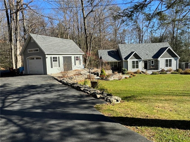 view of front of property featuring a front yard, an outbuilding, and a garage