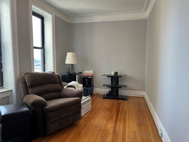 sitting room with light wood-type flooring, plenty of natural light, crown molding, and baseboards
