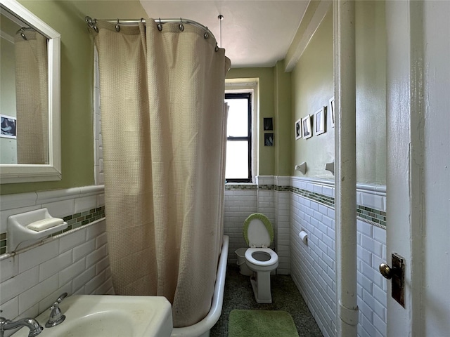 full bathroom featuring tile walls, a sink, wainscoting, and toilet