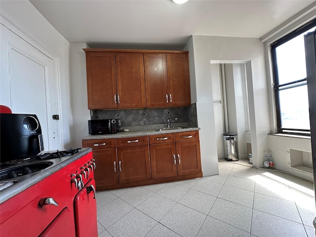 kitchen with backsplash, a sink, brown cabinets, and black microwave