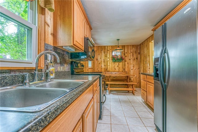 kitchen with wood walls, sink, decorative backsplash, light tile patterned floors, and appliances with stainless steel finishes