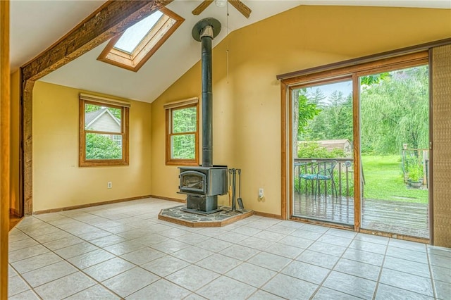 unfurnished living room featuring a wood stove, ceiling fan, light tile patterned floors, and lofted ceiling with skylight