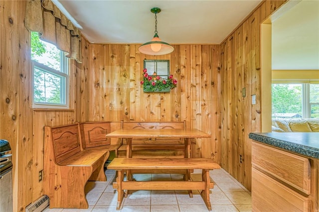 tiled dining space with a wealth of natural light, baseboard heating, and wooden walls