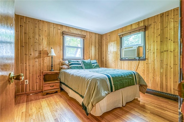 bedroom with wood-type flooring, a baseboard radiator, and wood walls