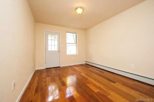 spare room with hardwood / wood-style floors and a baseboard heating unit