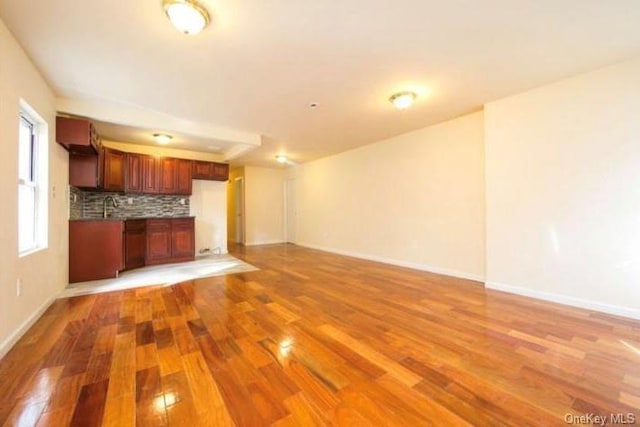 unfurnished living room featuring sink and light hardwood / wood-style flooring