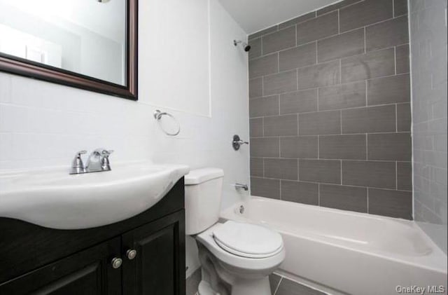 full bathroom with tiled shower / bath combo, backsplash, toilet, vanity, and tile walls