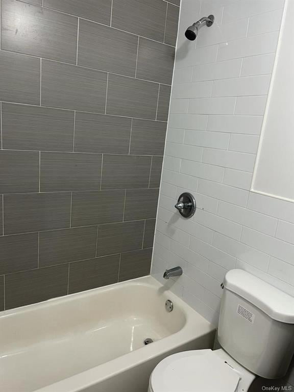 bathroom with tiled shower / bath combo and toilet