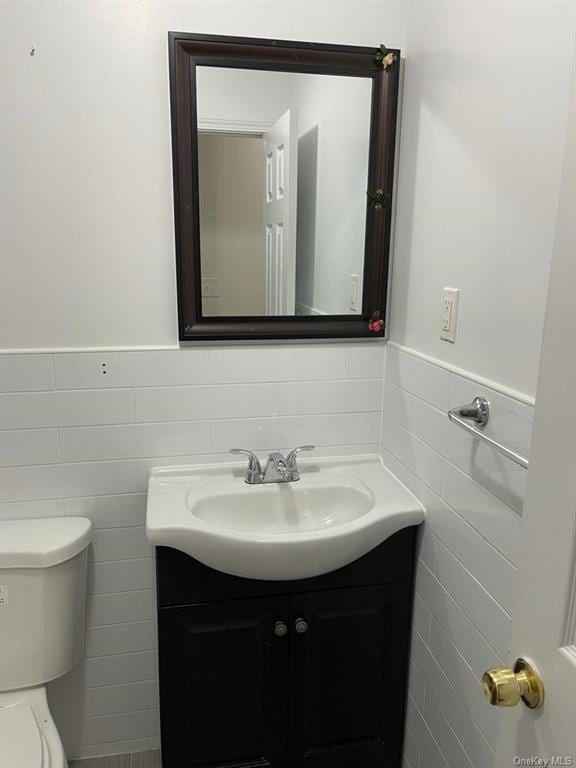 bathroom featuring vanity, toilet, and tile walls