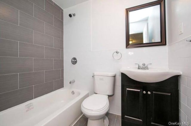 full bathroom with vanity, toilet, tile walls, and tiled shower / bath combo