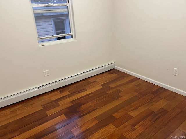 spare room featuring dark hardwood / wood-style flooring and a baseboard heating unit