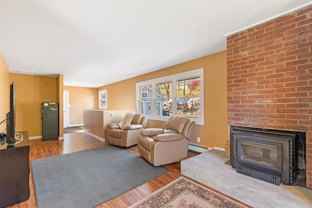 living room with baseboard heating, a fireplace, and hardwood / wood-style floors