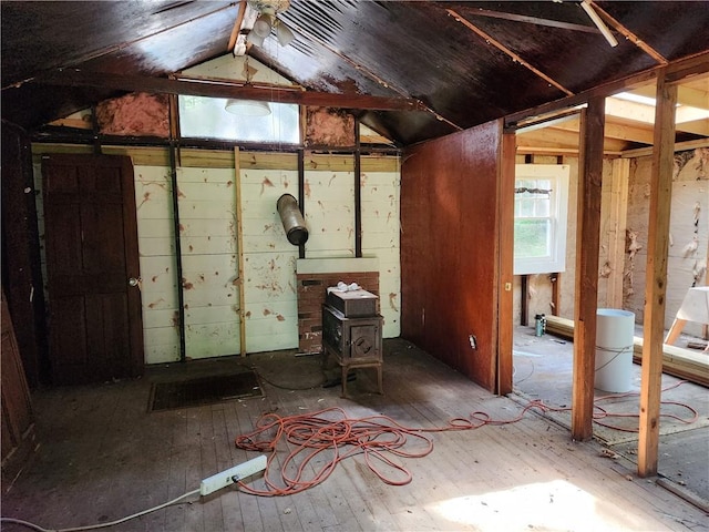 misc room featuring hardwood / wood-style floors, lofted ceiling, and a wood stove