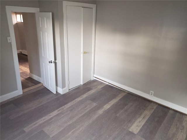 unfurnished bedroom with dark hardwood / wood-style floors and a closet