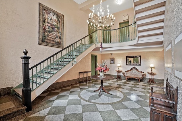 interior space featuring granite finish floor, a high ceiling, baseboards, and a chandelier