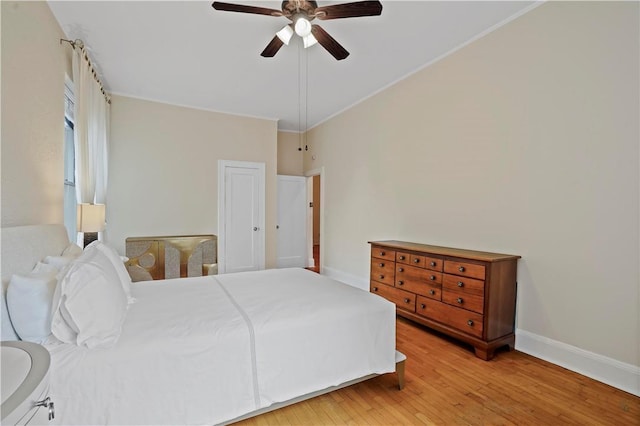 bedroom featuring ceiling fan, light wood finished floors, ornamental molding, and baseboards