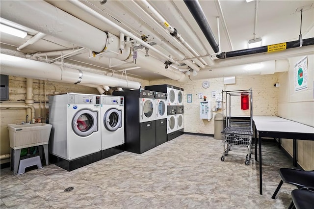 community laundry room with washing machine and dryer, stacked washer and clothes dryer, and electric panel