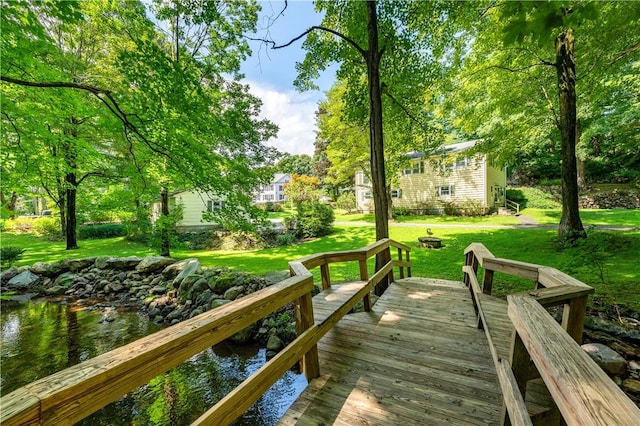 view of dock featuring a lawn and a deck with water view