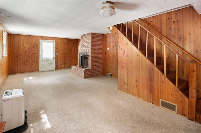 unfurnished living room with carpet, a fireplace, and wooden walls