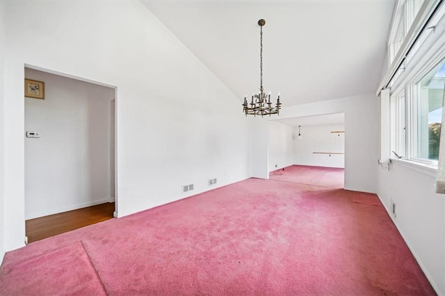 empty room featuring carpet floors, high vaulted ceiling, and an inviting chandelier