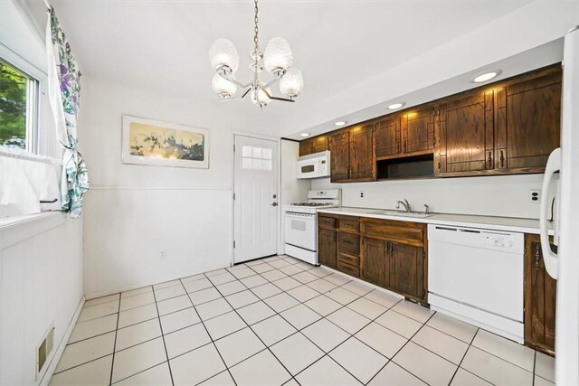 kitchen featuring sink, hanging light fixtures, a chandelier, white appliances, and light tile patterned floors