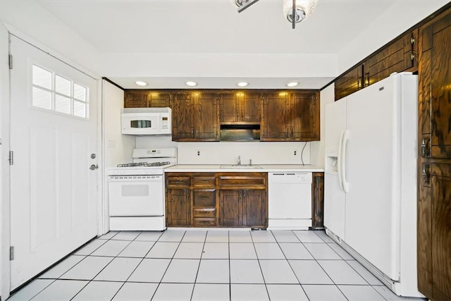 kitchen with dark brown cabinetry, sink, light tile patterned floors, and white appliances