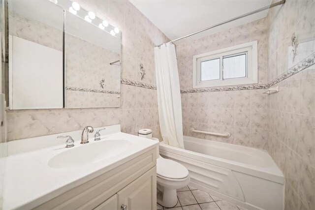 full bathroom with tile patterned floors, tile walls, toilet, vanity, and shower / tub combo