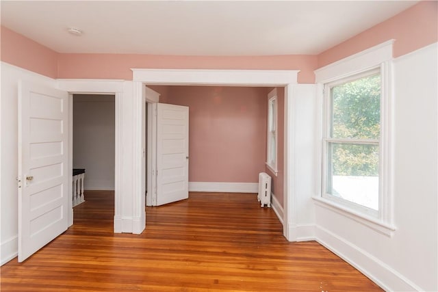 unfurnished bedroom with hardwood / wood-style floors and radiator