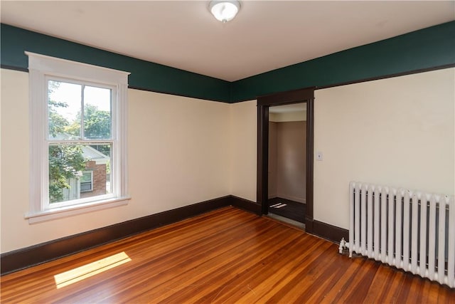 empty room featuring radiator heating unit and wood-type flooring