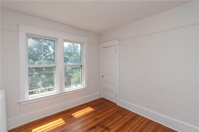 empty room with dark hardwood / wood-style floors and a healthy amount of sunlight