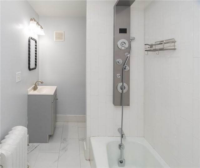 bathroom with radiator, vanity, and tiled shower / bath