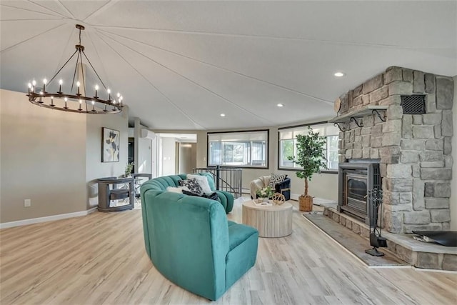 living room with a chandelier, a wood stove, light wood-type flooring, and a wall unit AC