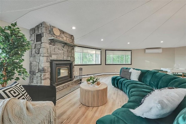 living room featuring a textured ceiling, a baseboard radiator, light hardwood / wood-style flooring, an AC wall unit, and a fireplace