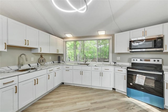 kitchen featuring white cabinetry, sink, light stone counters, light hardwood / wood-style floors, and appliances with stainless steel finishes