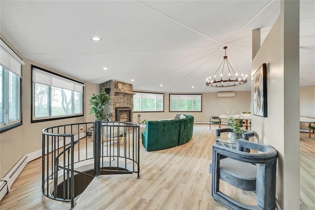 living room with light hardwood / wood-style floors, an inviting chandelier, a fireplace, and a wall mounted AC