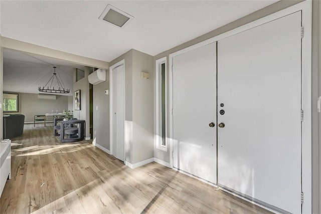 foyer entrance featuring light wood-type flooring and an AC wall unit