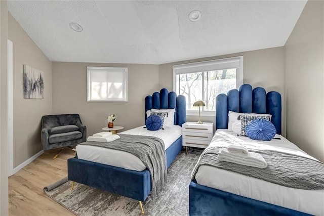 bedroom featuring wood-type flooring, a textured ceiling, and vaulted ceiling