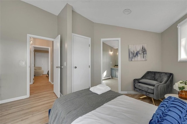 bedroom with ensuite bathroom, light hardwood / wood-style floors, a baseboard heating unit, and vaulted ceiling