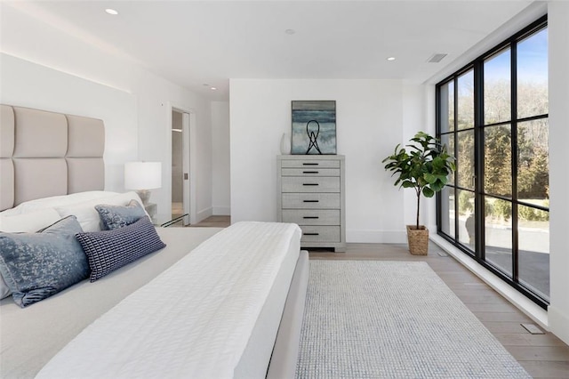 bedroom featuring wood-type flooring, access to outside, and multiple windows