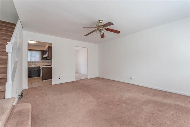 unfurnished living room featuring ceiling fan, sink, and light colored carpet