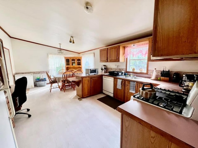 kitchen with kitchen peninsula, ornamental molding, stainless steel range, white dishwasher, and sink