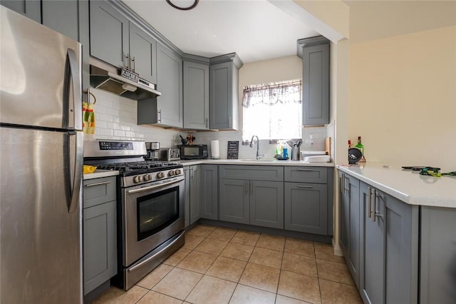 kitchen with appliances with stainless steel finishes, gray cabinets, sink, and light tile patterned floors