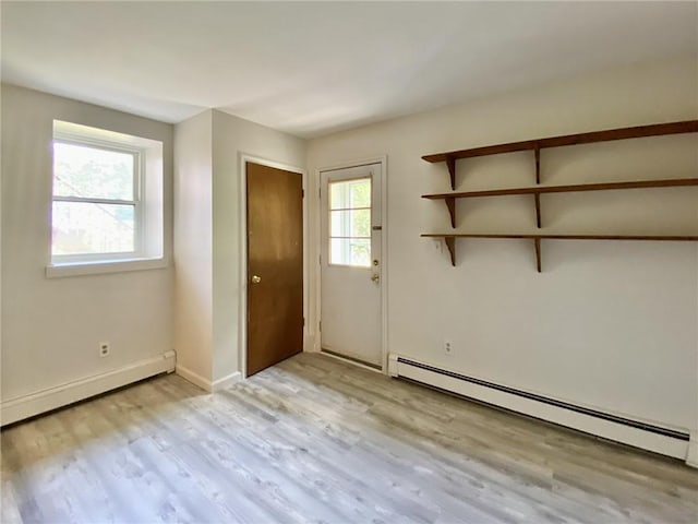 doorway with a wealth of natural light, light hardwood / wood-style floors, and a baseboard heating unit