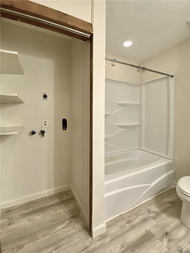 bathroom with hardwood / wood-style floors, toilet, and shower / washtub combination