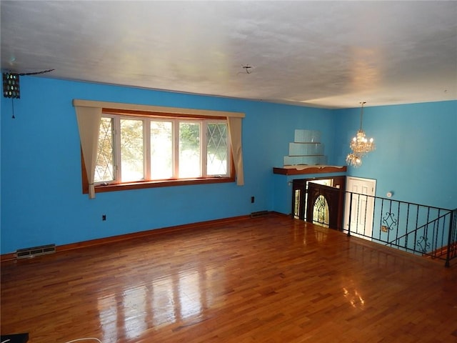 unfurnished living room featuring a chandelier and wood-type flooring